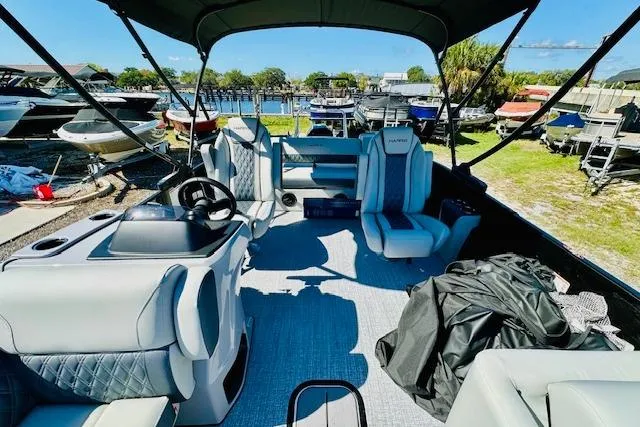 Slide: The Image of 2025 Harris Cruiser 250 pontoon boat interior with seating and helm, docked near other boats. - 11