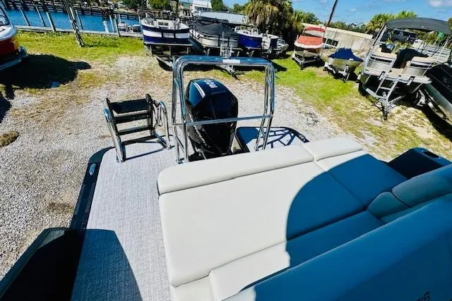 Slide: The Image of 2025 Harris Cruiser 250 pontoon boat with outboard motor, docked near a marina. - 18