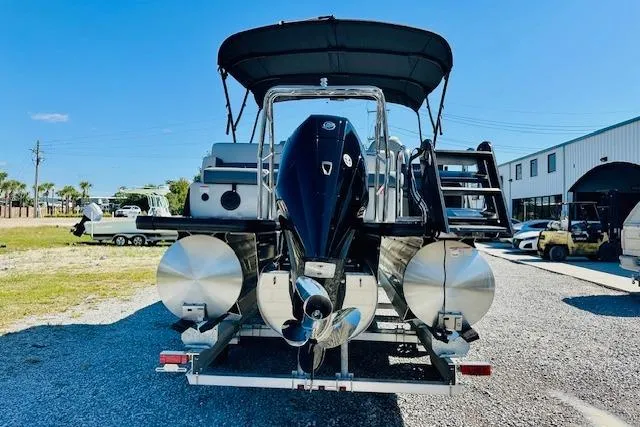 Slide: The Image of 2025 Harris Cruiser 250 pontoon boat with outboard motor, parked on gravel. - 2