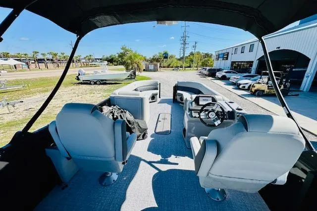 Slide: The Image of 2025 Harris Cruiser 250 interior with modern seating and steering, parked outdoors. - 21