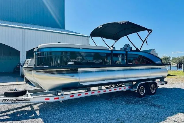 Slide: The Image of 2025 Harris Cruiser 250 pontoon boat on trailer, parked outdoors under clear sky. - 5