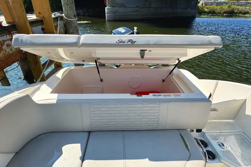 Slide: The Image of 2021 Sea Ray SPX 230 Outboard boat with open storage compartment by the water. - 4