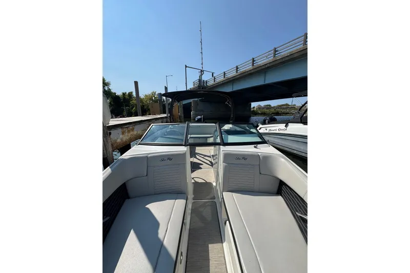 Slide: The Image of 2021 Sea Ray SPX 230 Outboard boat docked under a bridge, featuring spacious seating. - 6