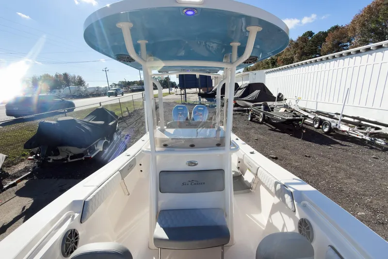 Slide: The Image of 2026 Sea Chaser 24 HFC DE boat interior with seating and console, parked outdoors. - 34