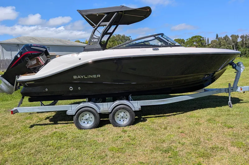 Slide: The Image of 2026 Bayliner V20 boat on trailer, parked on grass under blue sky. - 2