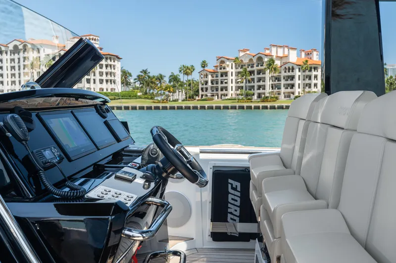 Slide: The Image of 2022 Fjord 44 Open yacht interior with luxury seating and modern dashboard, coastal view in background. - 25