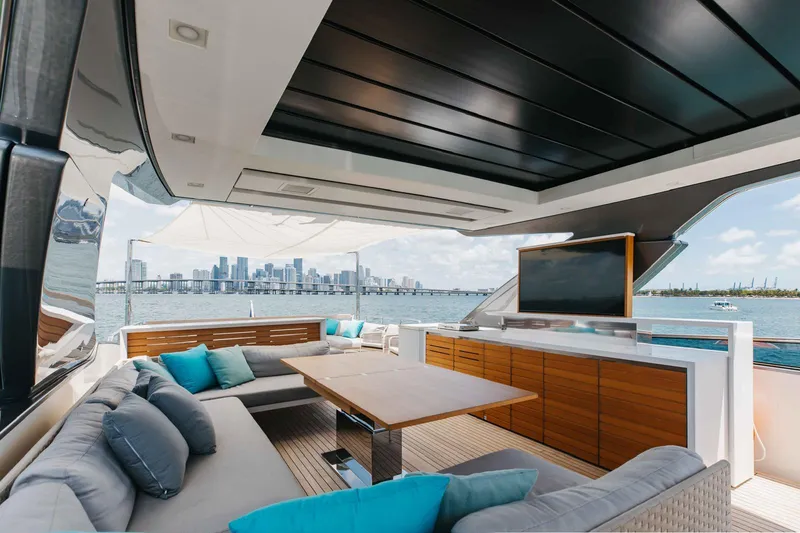 Slide: The Image of Luxurious 2022 Sanlorenzo SL86 yacht deck with city skyline view, featuring plush seating and a TV. - 2