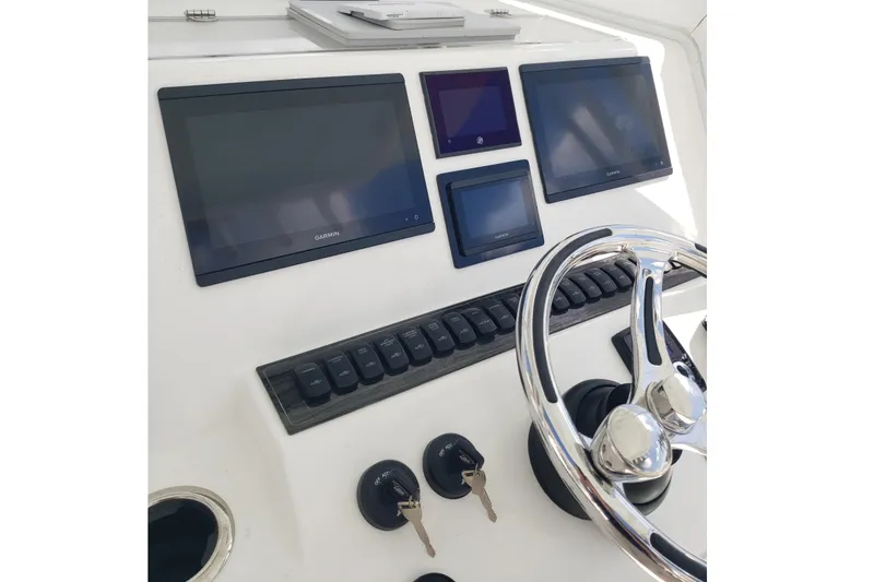 Slide: The Image of 2022 Albury Brothers 27 boat dashboard with Garmin displays and steering wheel. - 14