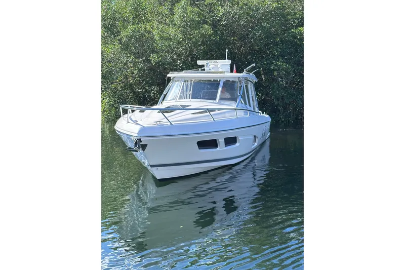 Slide: The Image of 2020 Intrepid 409 Valor boat on calm water, surrounded by lush greenery. - 11