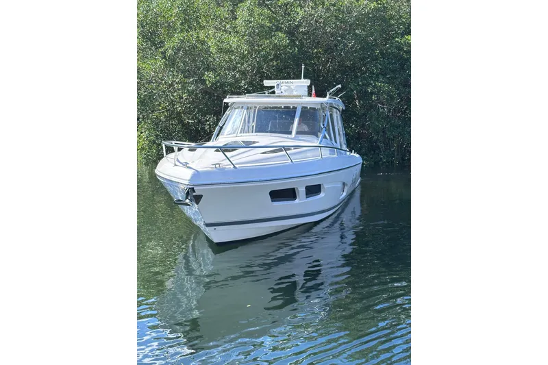 Slide: The Image of 2020 Intrepid 409 Valor boat on calm water, surrounded by lush greenery. - 12