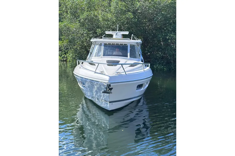 Slide: The Image of 2020 Intrepid 409 Valor boat on calm water, surrounded by lush greenery. - 13