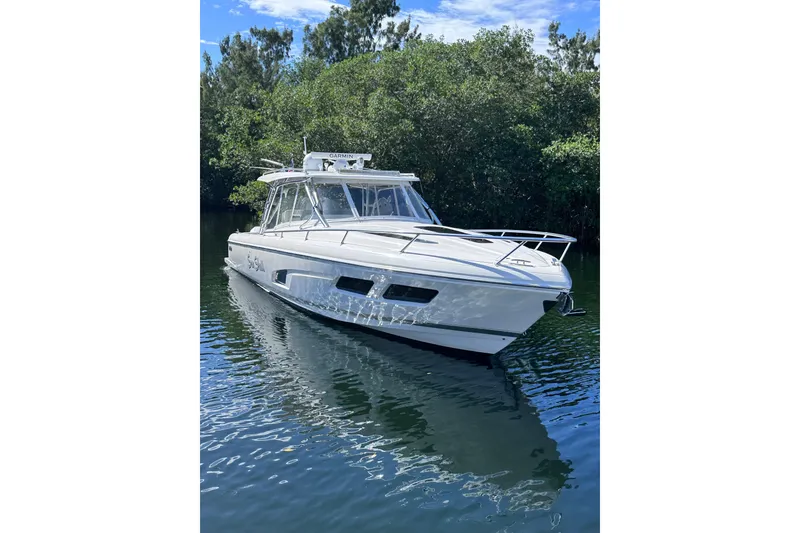 Slide: The Image of 2020 Intrepid 409 Valor boat on calm water, surrounded by lush greenery. - 15