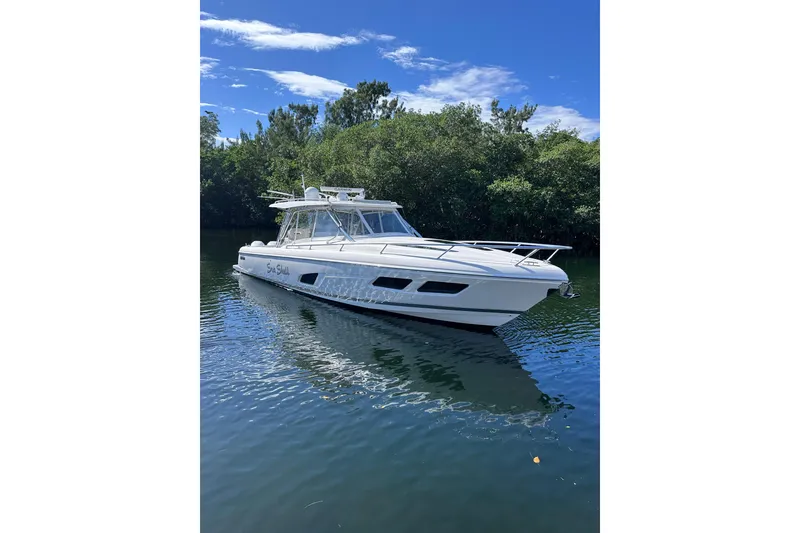Slide: The Image of 2020 Intrepid 409 Valor boat on calm water with lush greenery background. - 16