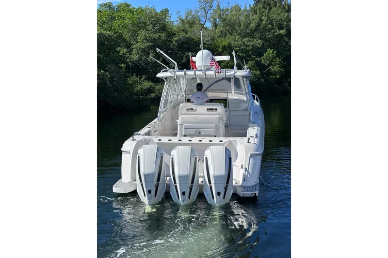 Slide: The Image of 2020 Intrepid 409 Valor boat with triple engines cruising on a calm waterway. - 3