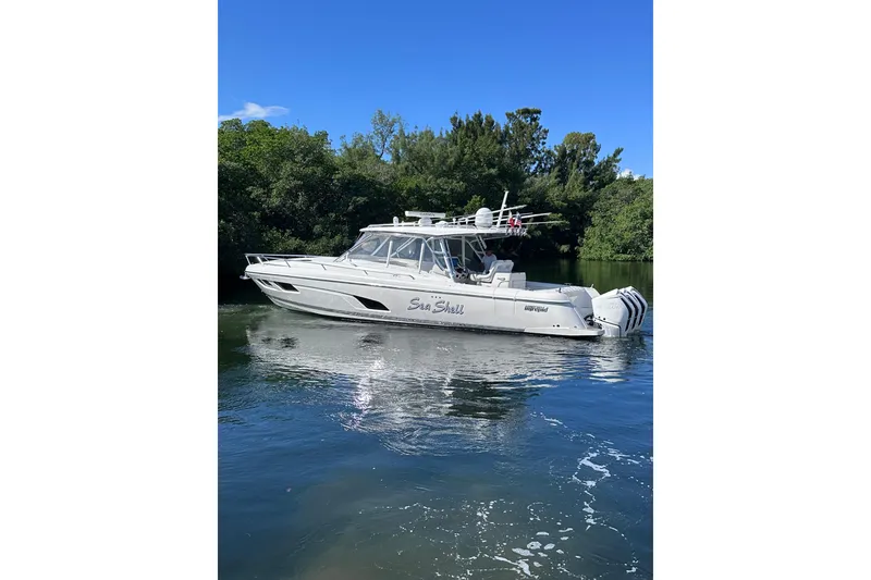 Slide: The Image of 2020 Intrepid 409 Valor boat on calm water, surrounded by lush greenery. - 6