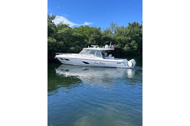 Slide: The Image of 2020 Intrepid 409 Valor boat cruising on a calm river with lush greenery. - 7
