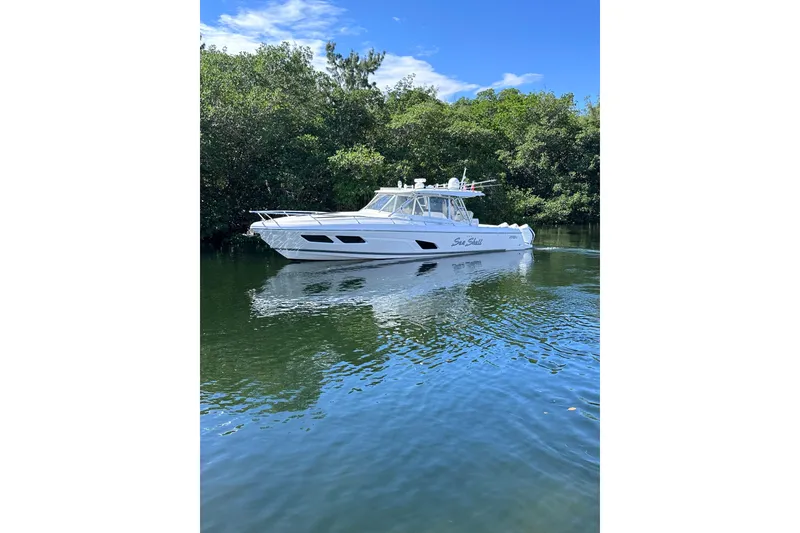 Slide: The Image of 2020 Intrepid 409 Valor boat cruising on a calm river with lush greenery. - 8