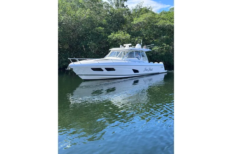 Slide: The Image of 2020 Intrepid 409 Valor boat on calm water, surrounded by lush greenery. - 9
