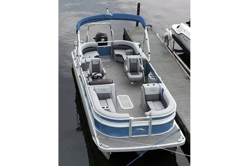 Slide: The Image of 2022 Bennington SX 23 Quad Bench pontoon boat docked, featuring spacious seating and sleek design. - 1