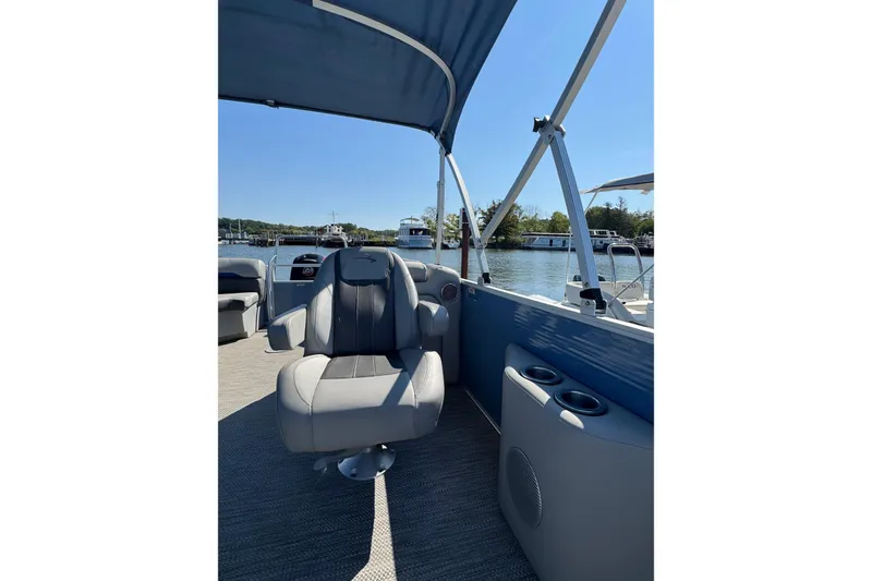 Slide: The Image of 2022 Bennington SX 23 Quad Bench boat interior with seating and cup holders on a sunny day. - 13