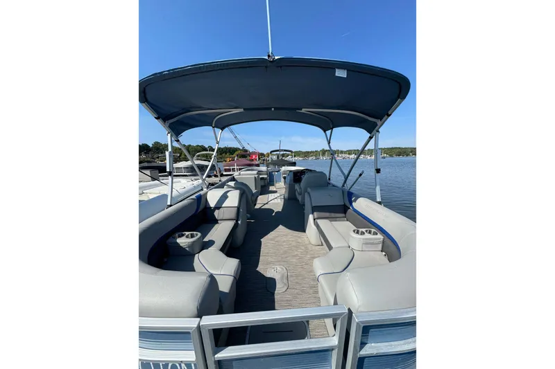 Slide: The Image of 2022 Bennington SX 23 Quad Bench pontoon boat with spacious seating and canopy on a sunny day. - 2