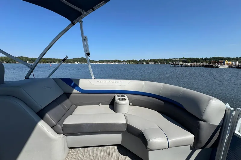 Slide: The Image of 2022 Bennington SX 23 Quad Bench pontoon boat on a serene lake. - 24