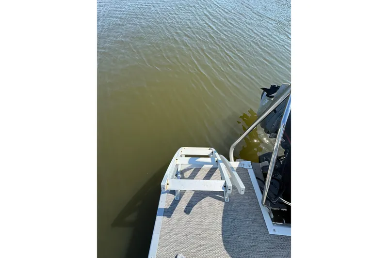 Slide: The Image of 2022 Bennington SX 23 Quad Bench boat with swim ladder and motor on calm water. - 25