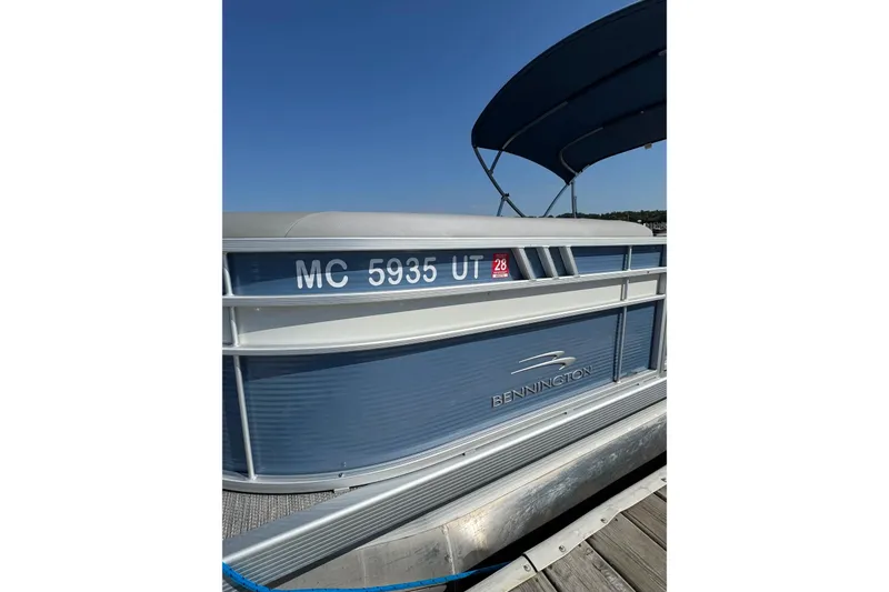 Slide: The Image of 2022 Bennington SX 23 Quad Bench pontoon boat docked under clear blue sky. - 4