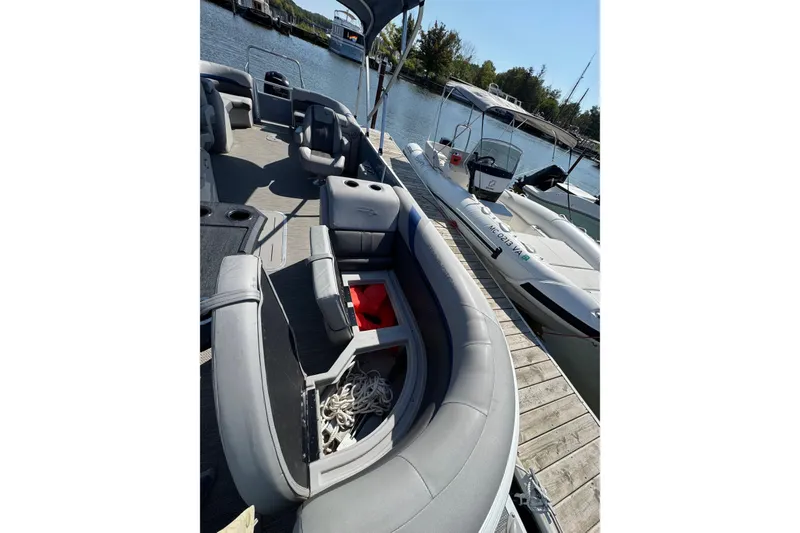 Slide: The Image of 2022 Bennington SX 23 Quad Bench pontoon boat docked, featuring spacious seating and storage. - 8