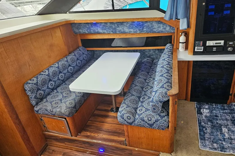 Slide: The Image of 1988 Silverton 37 Motor Yacht interior with blue patterned seating and white table. - 14