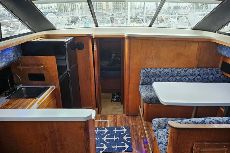 Slide: The Image of 1988 Silverton 37 Motor Yacht interior with kitchenette, dining area, and wood accents. - 16