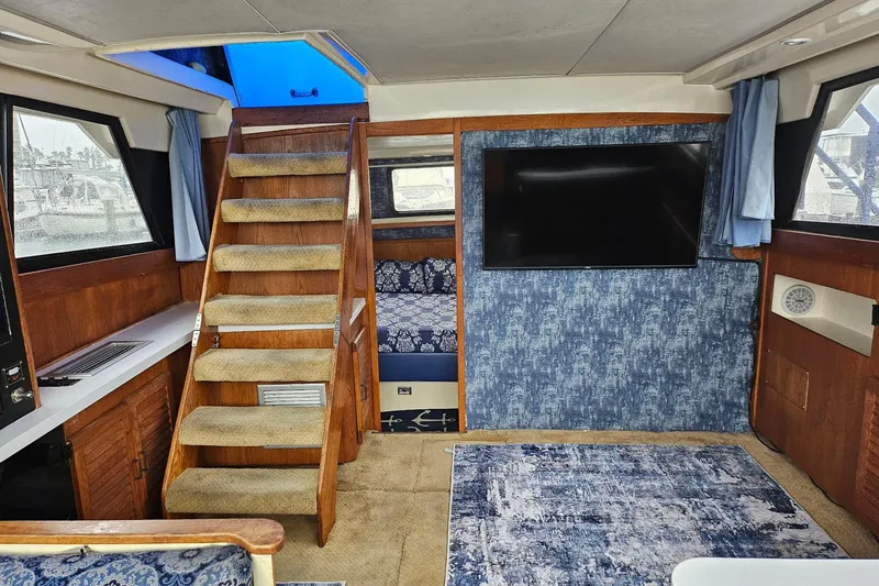 Slide: The Image of Interior of 1988 Silverton 37 Motor Yacht with stairs, TV, and blue decor. - 18