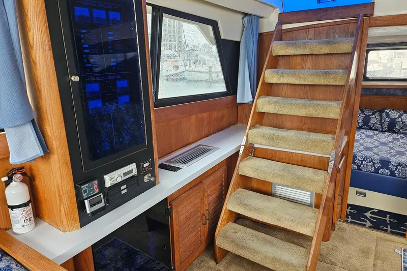 Slide: The Image of 1988 Silverton 37 Motor Yacht interior with carpeted stairs, control panel, and cozy cabin. - 19