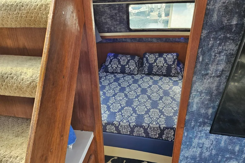 Slide: The Image of Interior of 1988 Silverton 37 Motor Yacht with blue floral bedding and wooden stairs. - 22