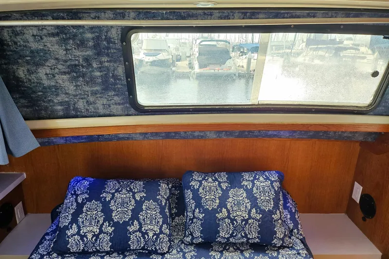 Slide: The Image of Interior of 1988 Silverton 37 Motor Yacht with patterned bedding and window view. - 25