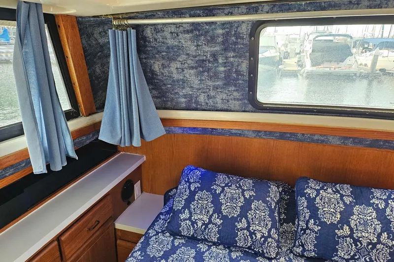 Slide: The Image of Interior of 1988 Silverton 37 Motor Yacht with blue floral bedding and curtains. - 26