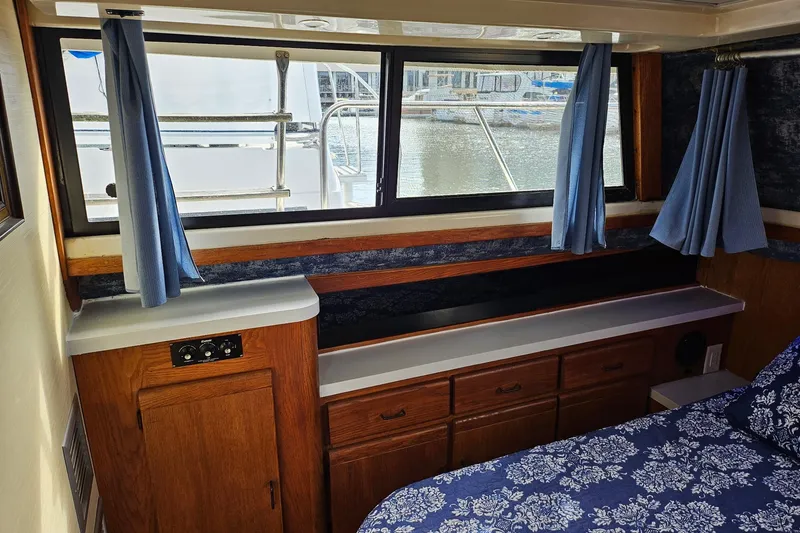 Slide: The Image of 1988 Silverton 37 Motor Yacht interior with wood cabinetry, blue curtains, and floral bedding. - 27