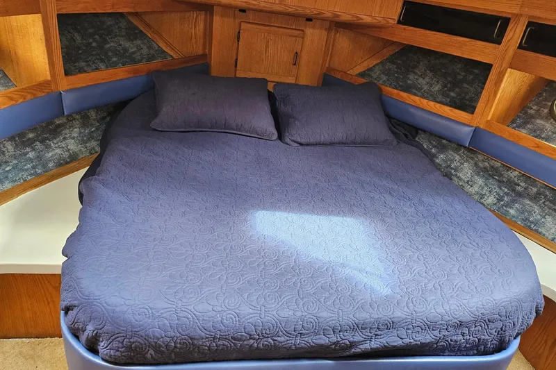 Slide: The Image of 1988 Silverton 37 Motor Yacht bedroom with blue bedding and wooden accents. - 28