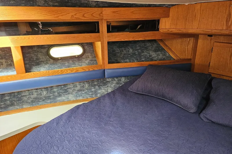 Slide: The Image of 1988 Silverton 37 Motor Yacht cabin with blue bedding and wooden interior. - 29