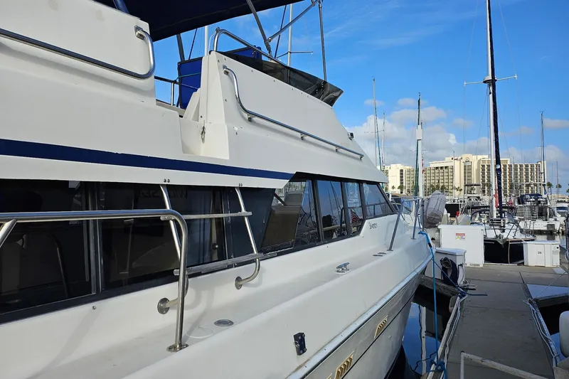 Slide: The Image of 1988 Silverton 37 Motor Yacht docked at marina, clear sky, modern buildings in background. - 5