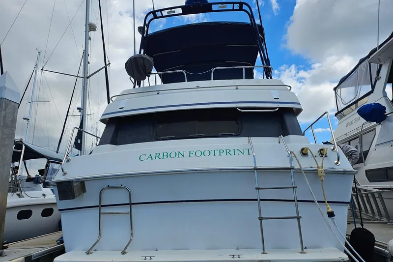 Slide: The Image of 1988 Silverton 37 Motor Yacht docked, named "Carbon Footprint," with blue sky background. - 7