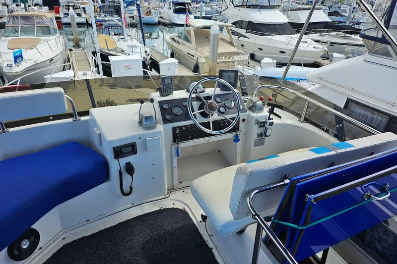 Slide: The Image of 1988 Silverton 37 Motor Yacht cockpit with steering wheel, controls, and marina view. - 9