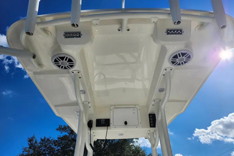 Slide: The Image of 2023 Sea Born FX22 Bay boat's T-top with speakers and rod holders under a sunny sky. - 44