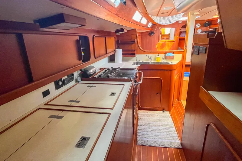 Slide: The Image of Interior of 1991 Oyster LW48 yacht, featuring a well-equipped kitchen and wooden cabinetry. - 20