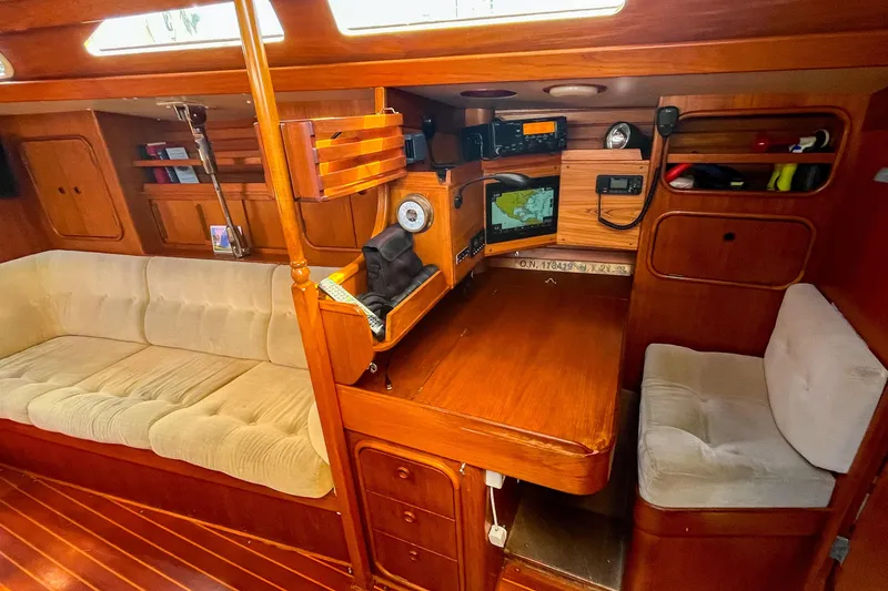 Slide: The Image of Cozy 1991 Oyster LW48 yacht interior with navigation station and plush seating. - 21