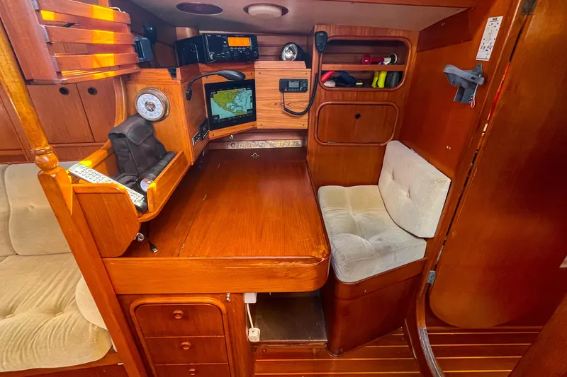 Slide: The Image of Cozy 1991 Oyster LW48 yacht interior with navigation station and seating area. - 22