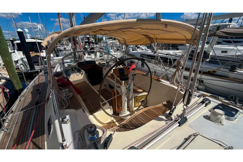 Slide: The Image of 1991 Oyster LW48 sailboat cockpit with steering wheel, canopy, and marina background. - 31