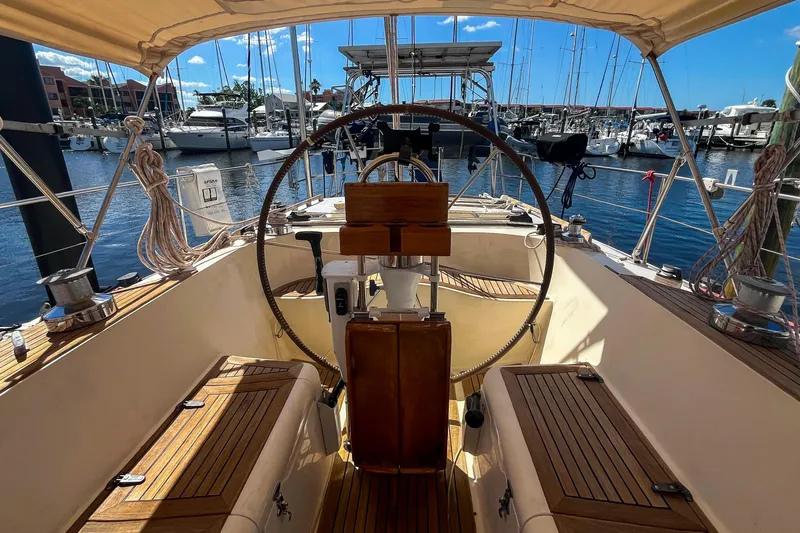 Slide: The Image of Cockpit view of 1991 Oyster LW48 sailboat docked at marina, featuring wooden seating and steering wheel. - 41