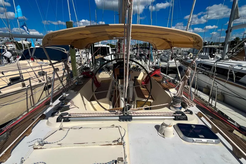 Slide: The Image of 1991 Oyster LW48 sailboat cockpit with canopy, docked at marina under blue sky. - 44