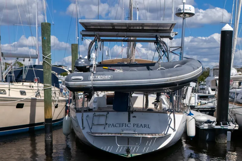 Slide: The Image of Sailboat "Pacific Pearl" docked, featuring a 1991 Oyster LW48 model with a tender on deck. - 49